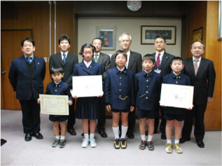 「エコポスター２００８」表彰式を挙行 前列左から山口君，菅野さん，西村君，田川君，新屋君懇談の様子 後列左から中之薗環境整備課長，古野教頭，嘉松副校長 片峰学長，田井村委員長，濱理事