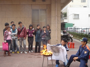 てんぷら鍋火災の初期消火を体験する留学生