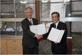 協定締結後，握手を交わす片峰学長（左） と坂井取締役社長