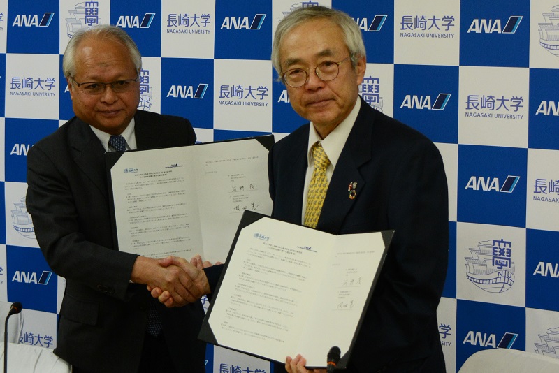 協定書を掲げる岡田代表取締役社長と河野学長