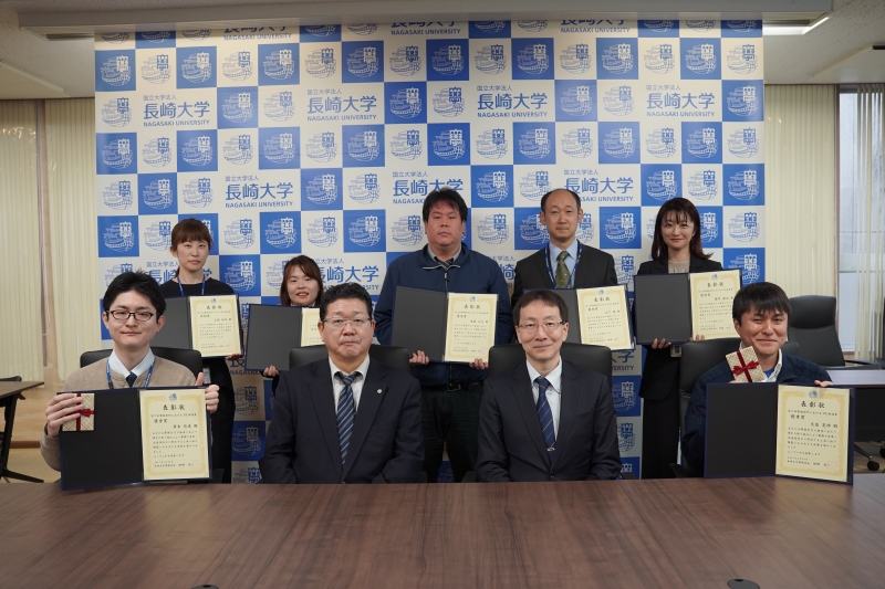 受賞者と田頭事務局長（前列中央左）、高田副学長（前列中央右）